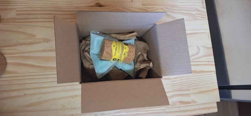 Colis de gelée royale prêt à partir : l'étui en liège calé au papier kraft dans son carton