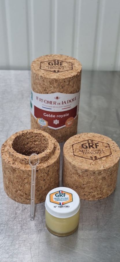 Pilulier de gelée royale ouvert devant son étui en liège, avec la cuillère doseuse